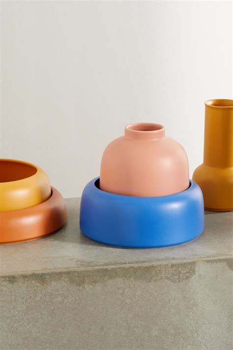 Three Different Colored Vases Sitting Next To Each Other On A Cement