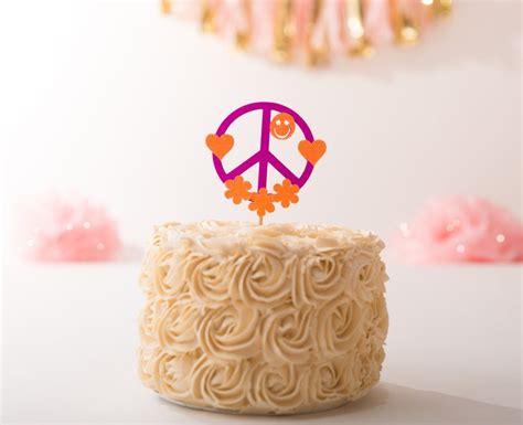 A Peace Sign Cake Topper Sitting On Top Of A White Frosted Cupcake