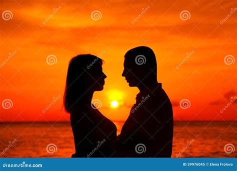 romantic couple kissing at tropical beach with sunset in the background stock image