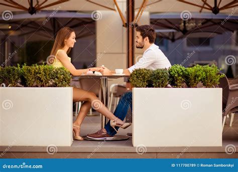 playful girlfriend is flirting with guy by her leg lovers are sitting in light cafe on a sunny