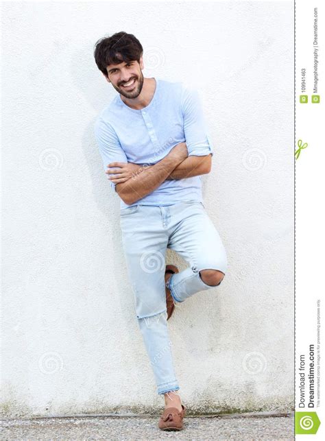 Full Body Smiling Male Fashion Model Leaning Against White Wall Stock