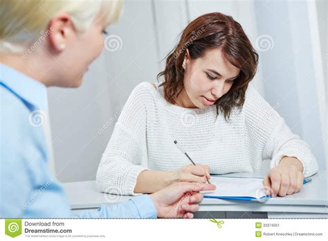 Female Patient At Doctor Filling Out Form Stock Image