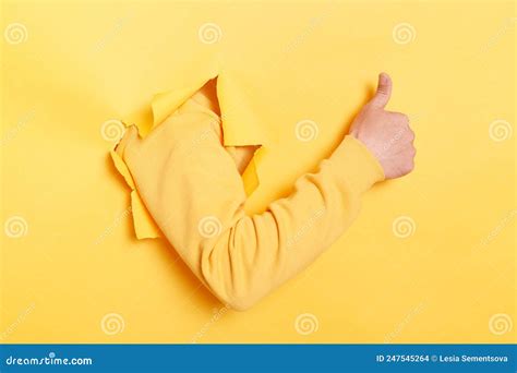 Indoor Shot Of Human Hand Breaks Arm Through Paper And Showing A Thumb