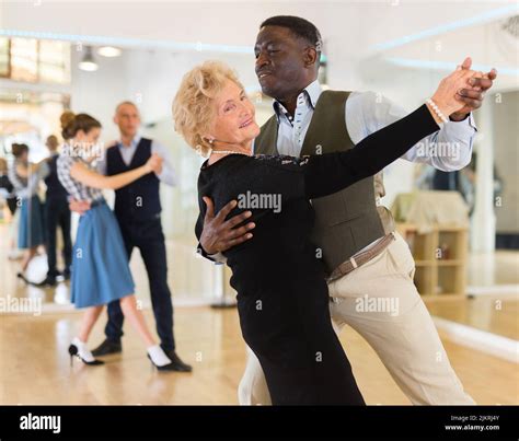 Elderly Woman Learning Ballroom Dancing In Pair In Dance Studio Stock