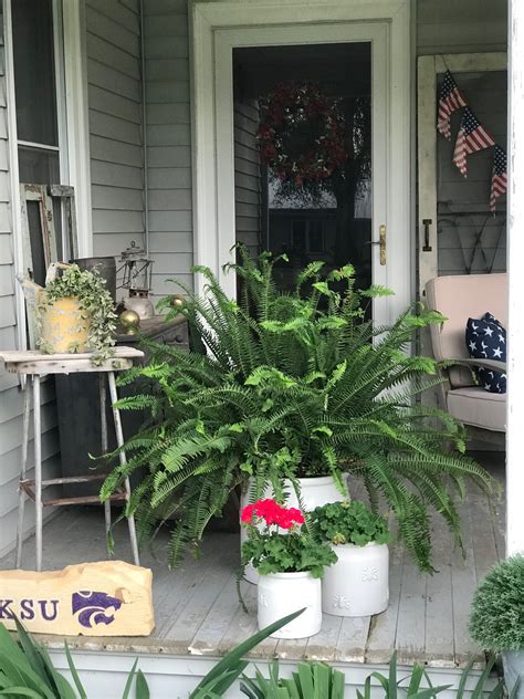 The Front Porch Is Decorated With Potted Plants