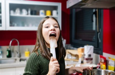 Uma Adolescente Chupa Os Dedos Manchados De Chocolate Em Sua Cozinha Foto Premium