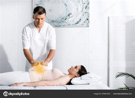 Focused Healer Standing Woman Massage Table Holding Hands Her Stomach