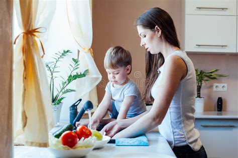 El Niño Pequeño Está Ayudando A La Mamá En La Cocina Foto De Archivo