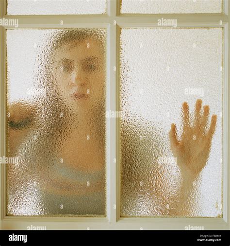 Woman Leaning Against Door Looking Through Window Stock Photo Alamy