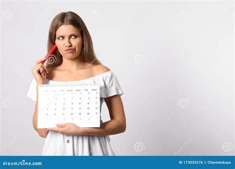 Pensive Young Woman Holding Calendar With Marked Menstrual Cycle Days
