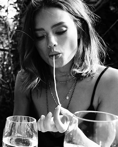 A Woman Sitting At A Table With Two Wine Glasses In Front Of Her And Drinking From A Straw