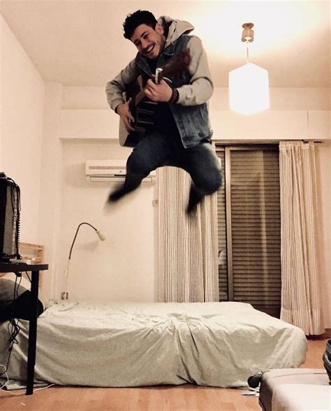 A Man Jumping In The Air Over A Bed
