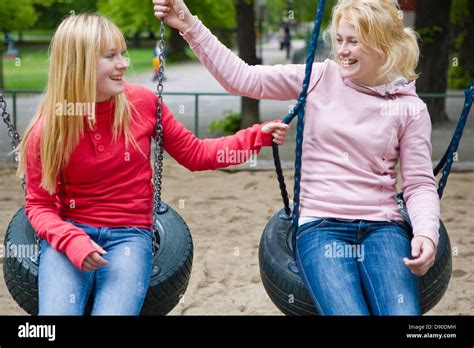 Two Smiling Teenage Girls Sitting On Tire Swings Stock Photo Alamy