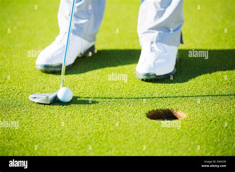 Man Putting Golf Ball Into The Hole Close Up Detail Shot Stock Photo