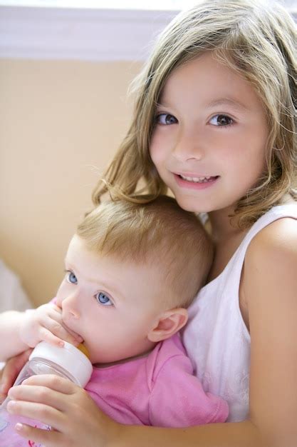 Premium Photo Toddler Girl Giving Bottle Of Milk To Baby Sister