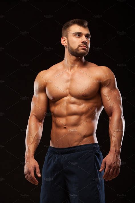 Fitness Muscular Man Is Posing And Showing His Torso With Six Pack Abs Isolated On Black