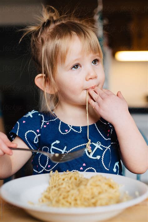 Cute Toddler Girl In Blue Dress Eating Ramen Noodles At The Kitchen