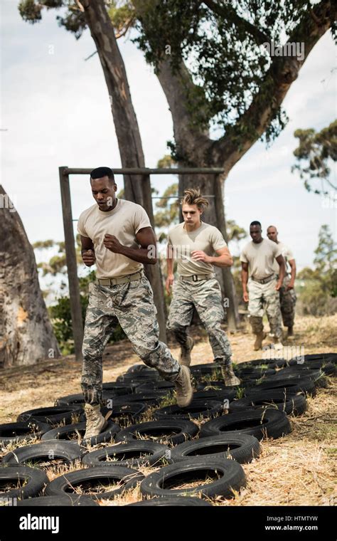 Young Military Soldiers Practicing Tyre Obstacle Course At Boot Camp