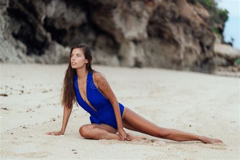 Tanned Model In Blue Swimwear Posing On White Sandy Beach Stock Photo