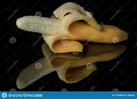 Half Peeled Banana On A Black Mirror Surface With Reflections Isolated