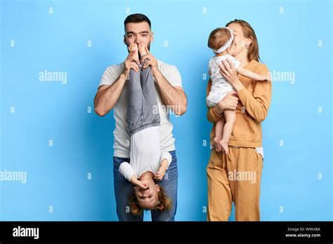 Dad Holding His Child Upside Down And Kissing Her Feet While His Wife