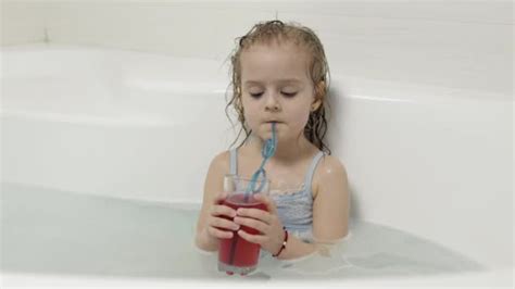 Cute Blonde Girl Takes A Bath In Swimwear And Drinking A Cocktail