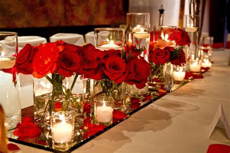 Romantic Centrepiece Of Red Roses And Candle Light Sitting On Top Of A