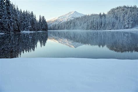 Mountain Reflecting In Lake In Winter With Snow Stock Photo