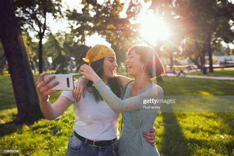 Beautiful Young Lesbian Couple Having Fun Taking Selfies At A Park High