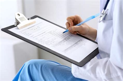 Female Doctor Filling Up Medical Form On Clipboard Closeup Physician