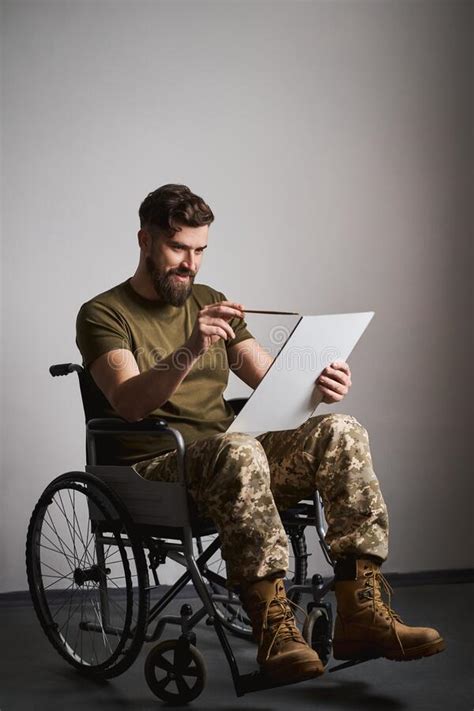 Happy Military Man Sitting In A Wheelchair And Watching Album Photos