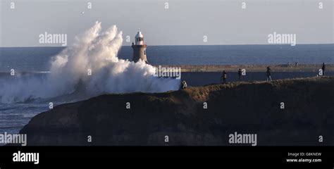 Bystanders Watch Giant Waves Crash Over The Tynemouth Pier Hi Res Stock