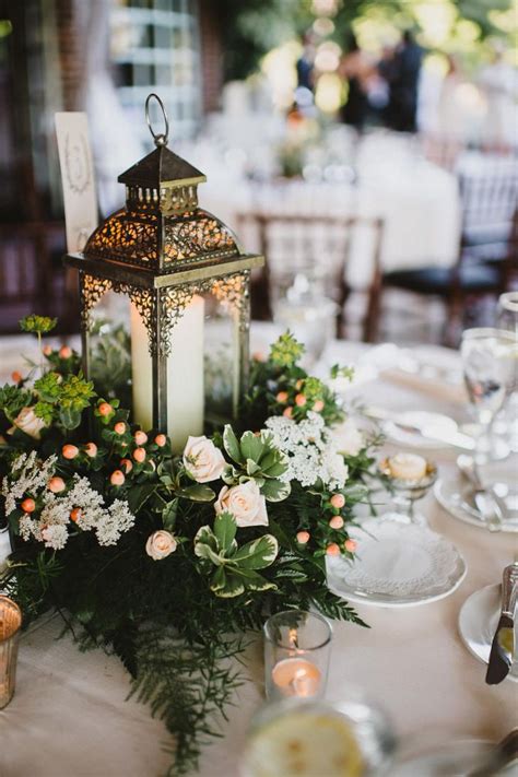 Wedding table decorations set the tone for your reception. Lantern and Greens Centerpiece in 2019 | Lantern ...