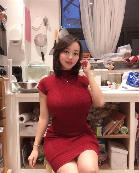 A Woman In A Red Dress Is Sitting On A Chair And Posing For The Camera