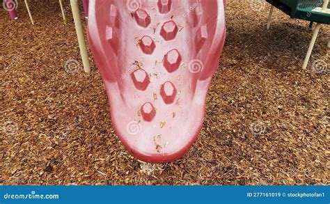 Red Plastic Playground Slide With Wood Chips On Ground Stock Image