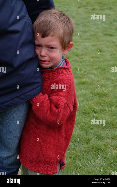Little Boy Crying And Holding Onto His Mothers Leg Stock Photo Alamy