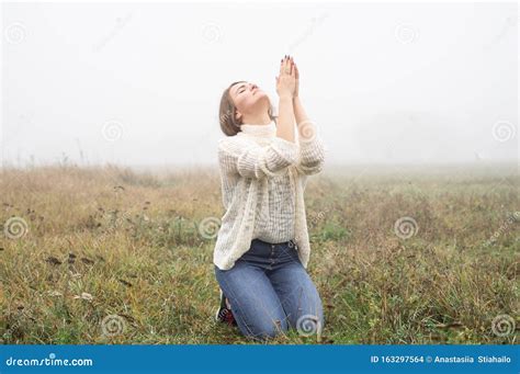 Girl Closed Her Eyes On The Knees Praying In A Field During Beautiful