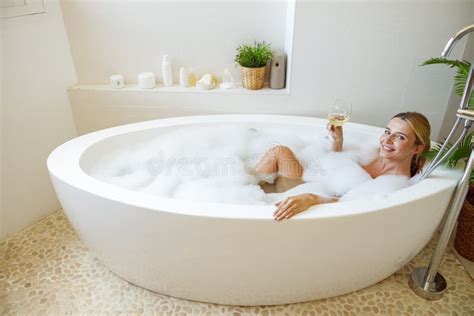 Blonde Beautiful Young Woman Lying In Bathtub With Foam And Holding