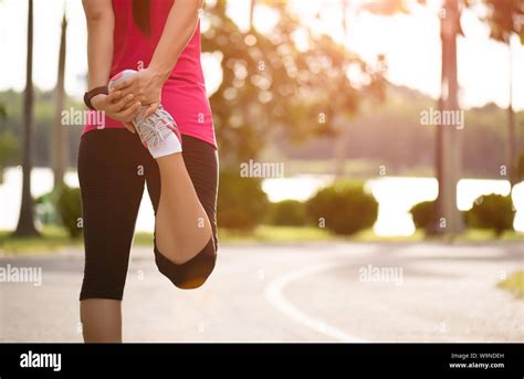 Young Fitness Woman Runner Stretching Legs Before Run In The Park