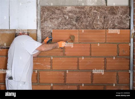 Construction Worker Laying Bricks After Placing An Acoustic And Thermal