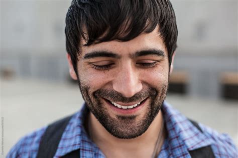 A Man With Dark Hair And Beard Smiling And Looking Down Del