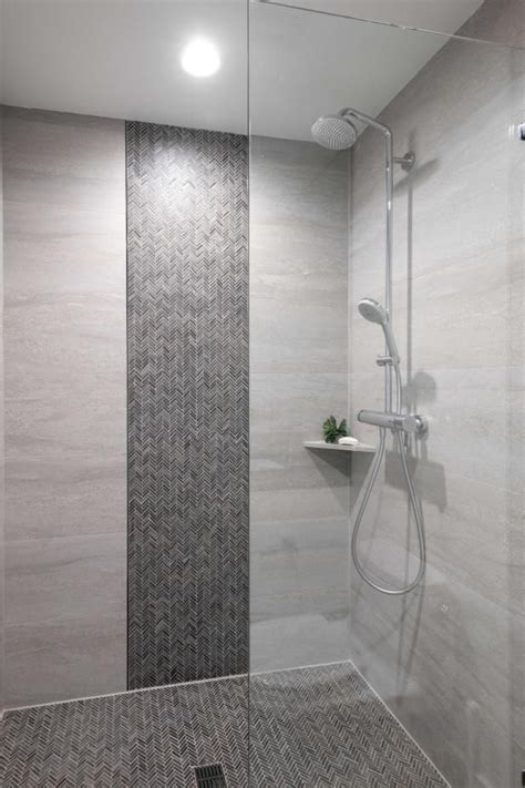 A Walk In Shower Sitting Next To A Tiled Wall And Floor Covered In Grey