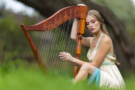 Natural Portrait Of Sensual Female Harpist Woman In Light Dress Playing