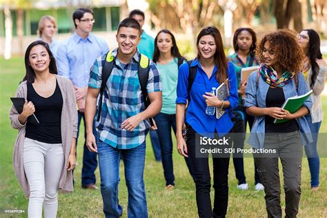 Diverse Group Of College Students Walking On Beautiful Campus Stock