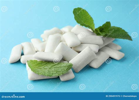 Pile Of Tasty White Chewing Gums And Mint Leaves On Light Blue