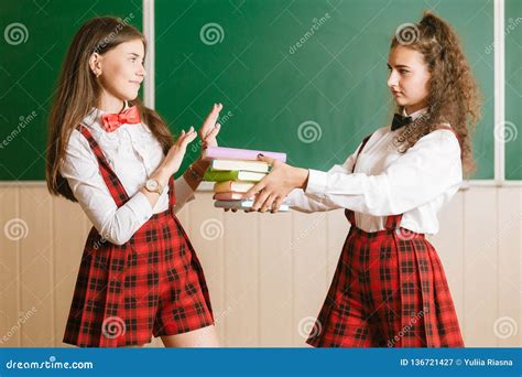 Zwei Brunette Schulmädchen In Den Schulroten Uniformen Stehen In Einem Klassenzimmer