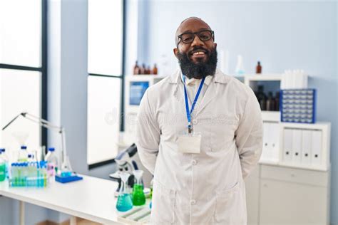 Young African American Man Wearing Scientist Uniform Standing At