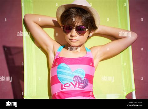 Young Girl Wearing Swimwear Sunglasses And A Sun Hat Sitting In Sun