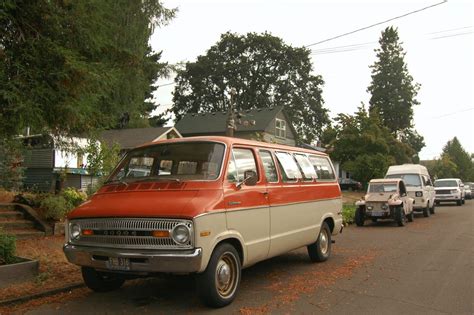 An Orange And White Van Parked On The Side Of A Road Next To Other Cars