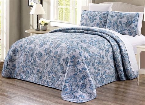 A Blue And White Comforter Set With Pillows On Top Of A Bed In A Bedroom